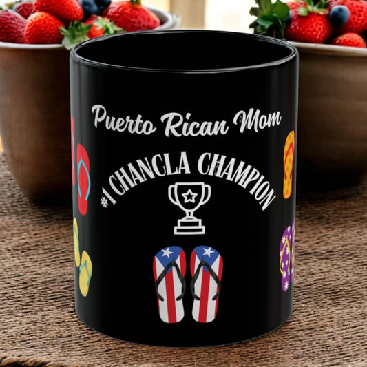 Black mug with 'Puerto Rican Mom Chancla Champion' text and flip-flop design on a wooden surface with bowls of strawberries and blueberries.